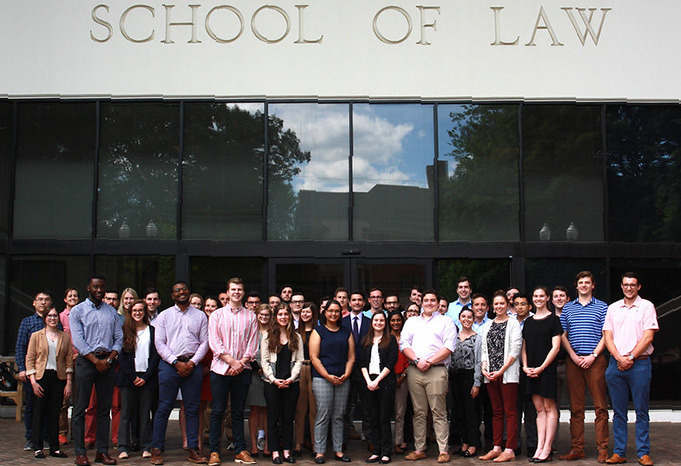 Group of people posed in front of Emory Law building